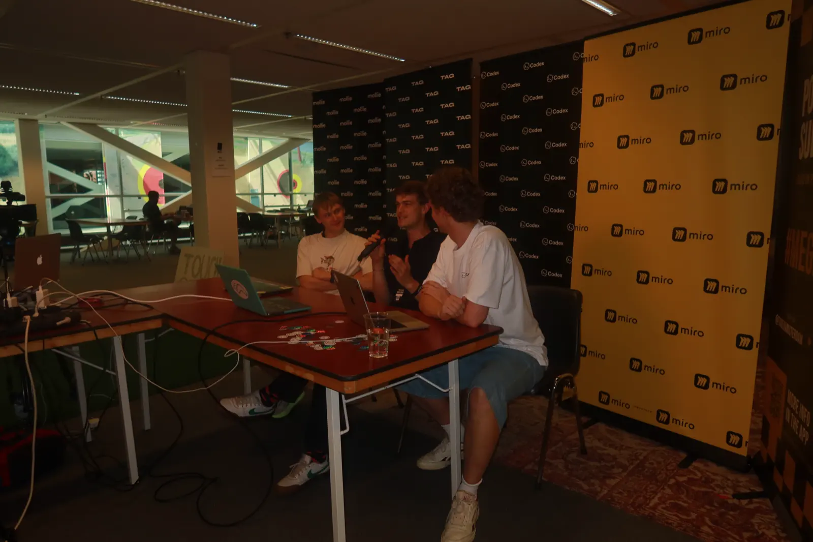 Maximilian Lehmann spricht mit Mikrofon beim Megathon zwischen zwei Gesprächspartnern